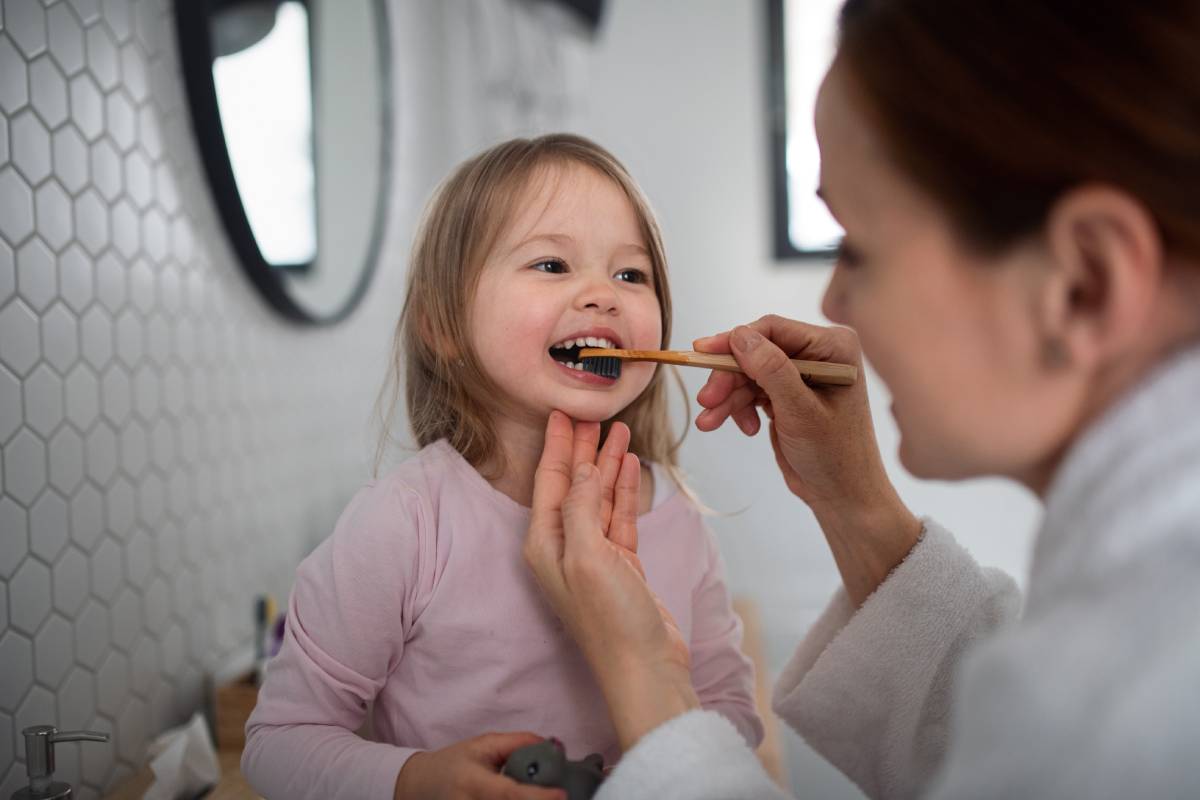 mother brushing her daughters teeth