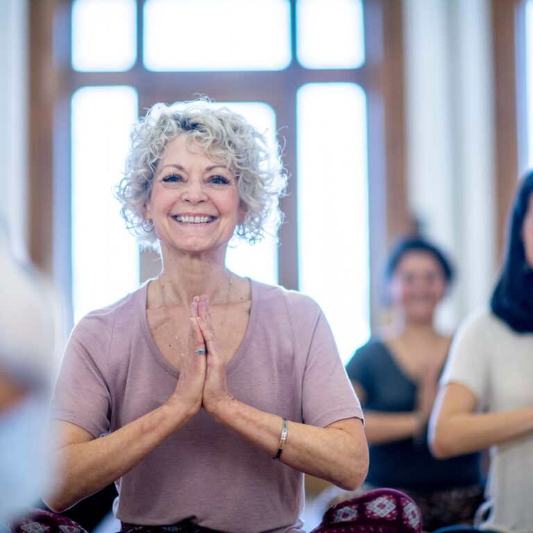 Older woman with beautiful smile participates in a yoga class.