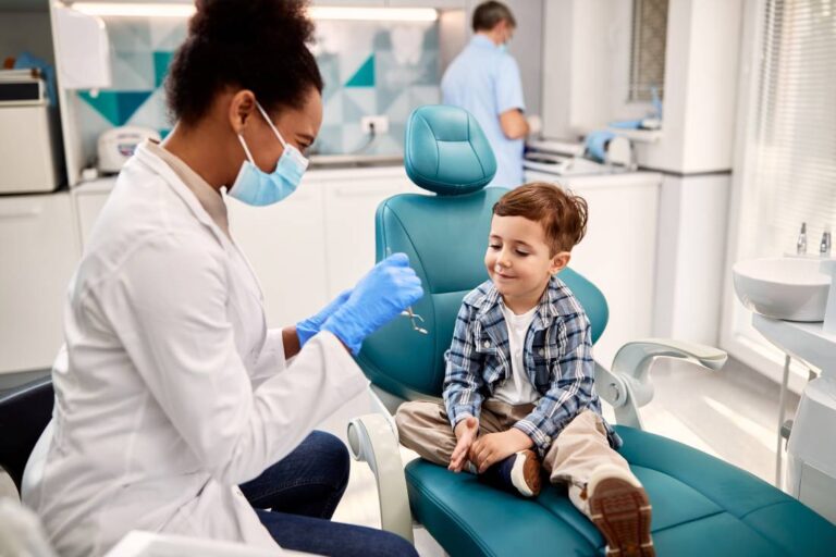 Young child sits in dental exam chair while the dentist speaks to him