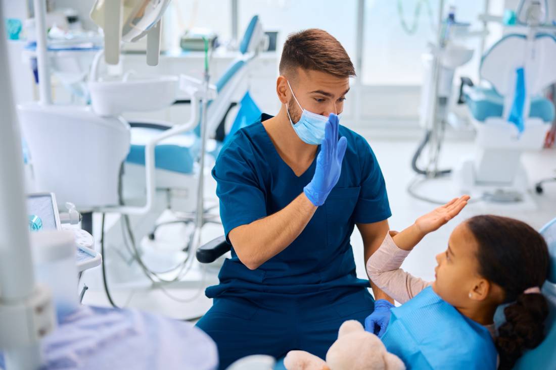 Dentist and young child patient are high fiving.