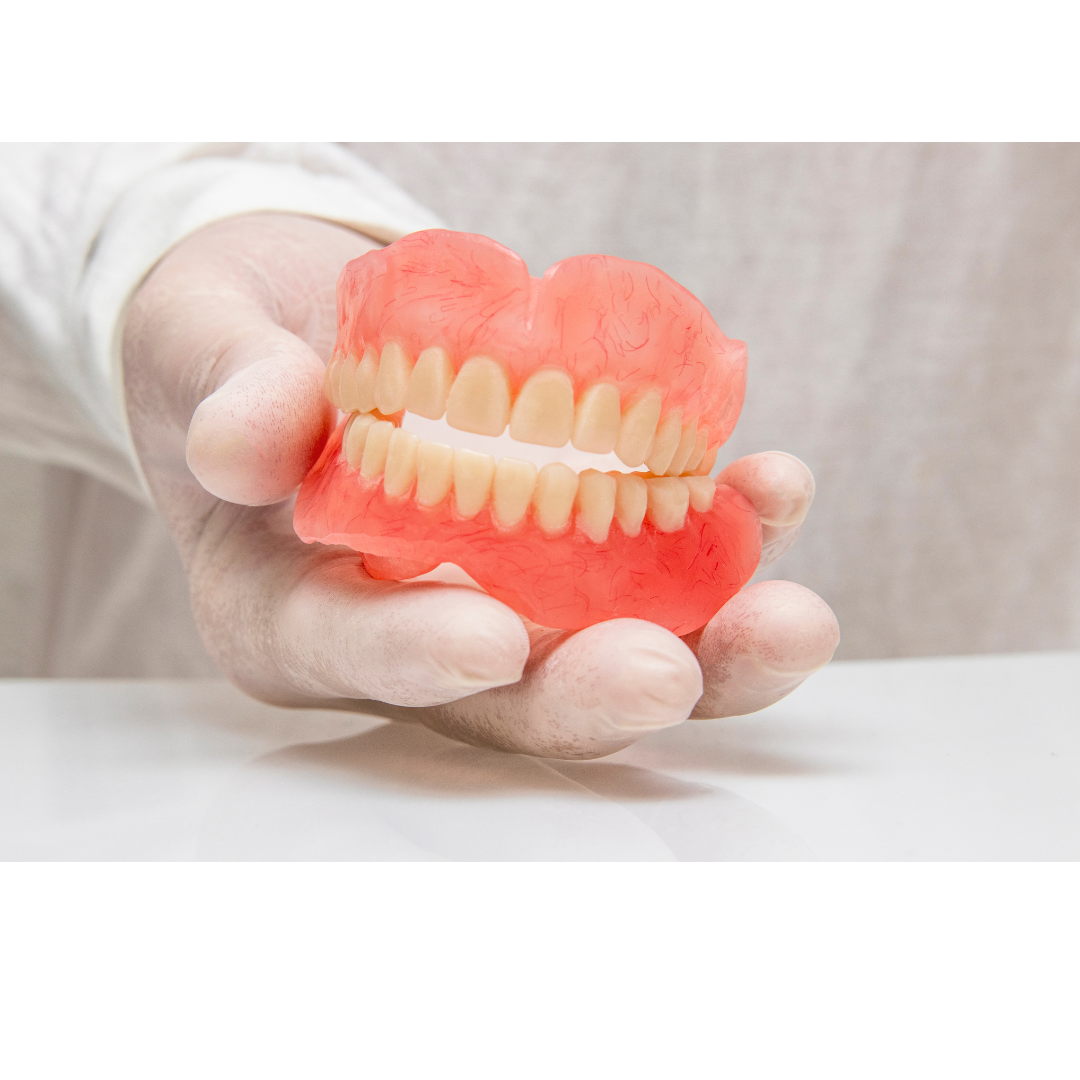 Close up of a person holding dentures