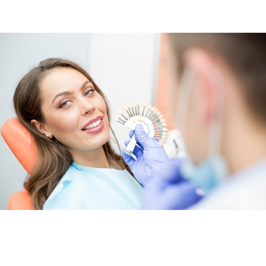 Dental patient smiles while a technician matches her tooth shade.