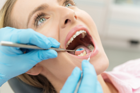 Patient of Ames Dentistry opens mouth, while a dentist  performs an exam.